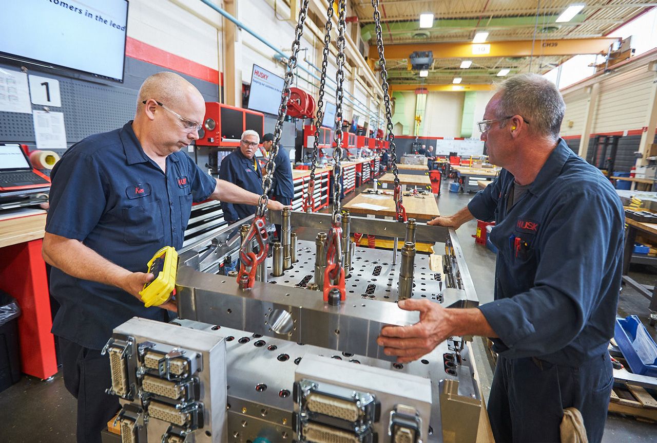 Techniker von Husky arbeiten an einem Spritzgießsystem