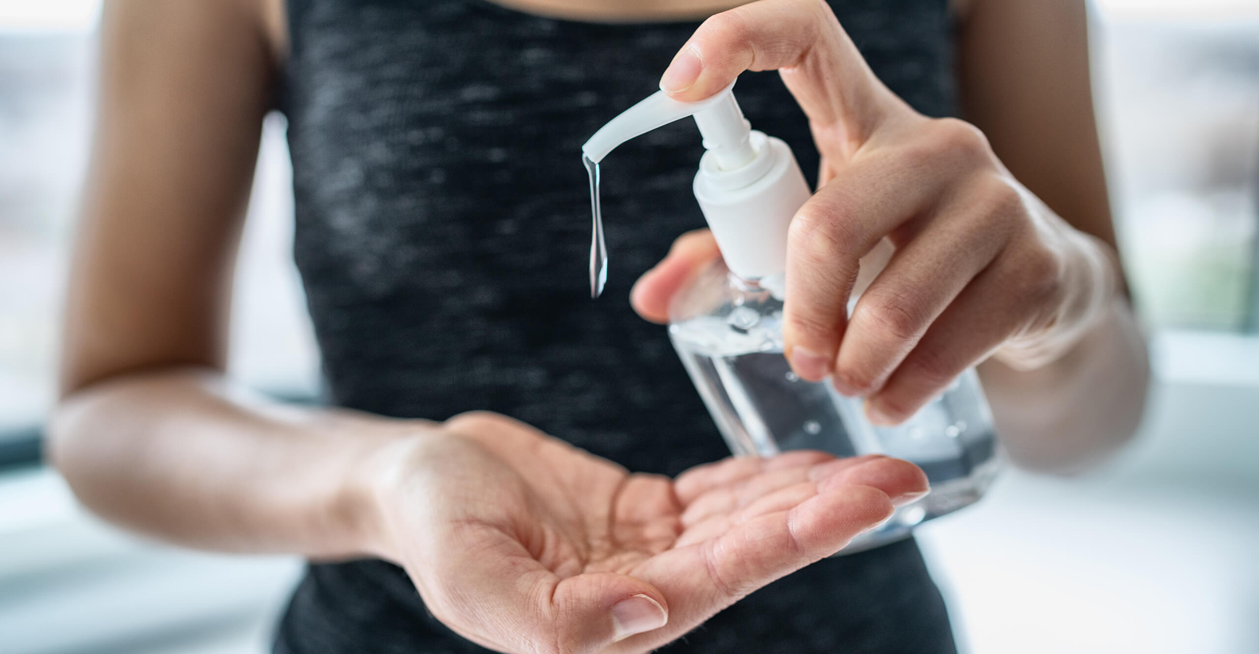 Woman using hand sanitizer from a bottle manufactured using medical injection molding