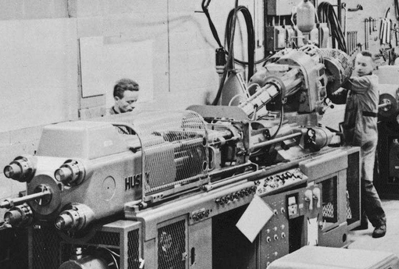 Ein altes Foto von Technikern von Husky beim Betrieb einer Spritzgießanlage